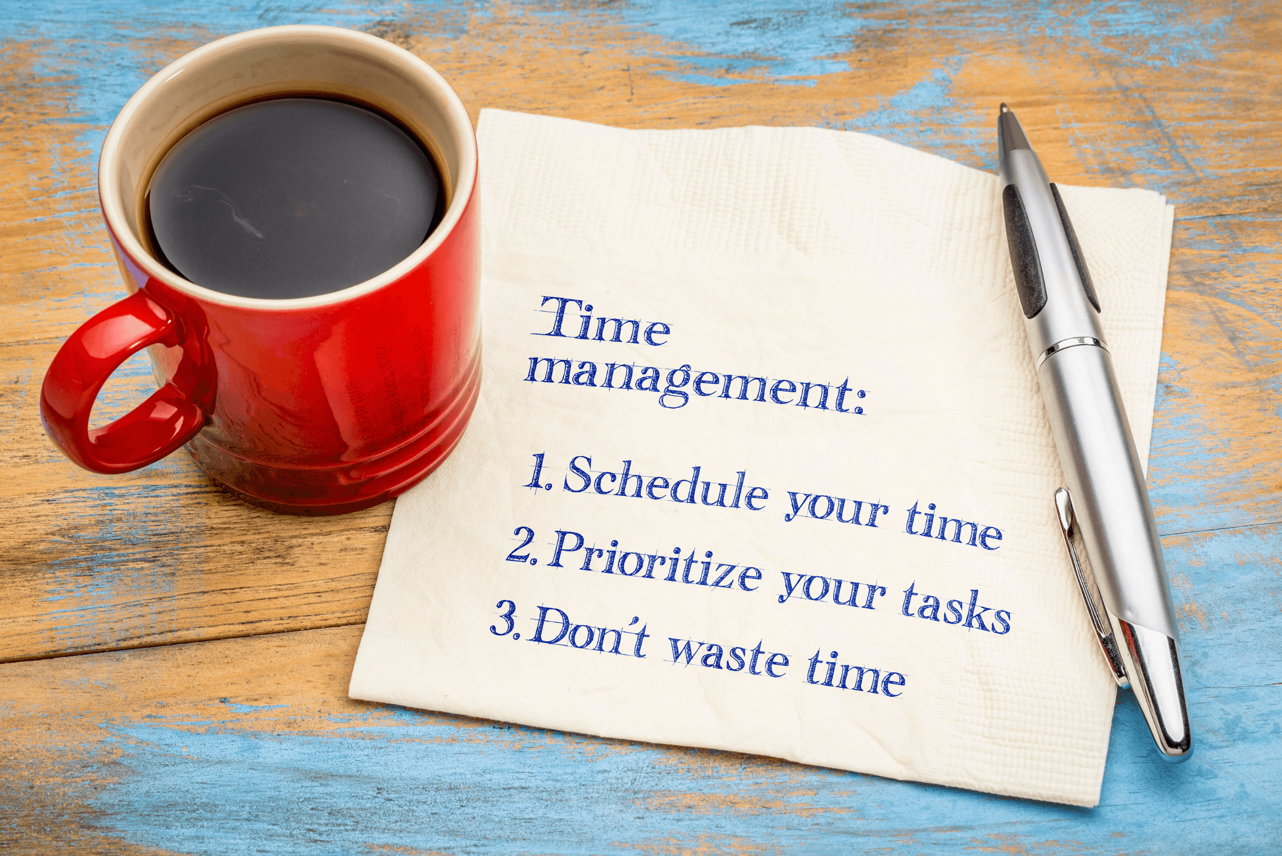 Desktop with coffee cup and piece of paper listing time management tips