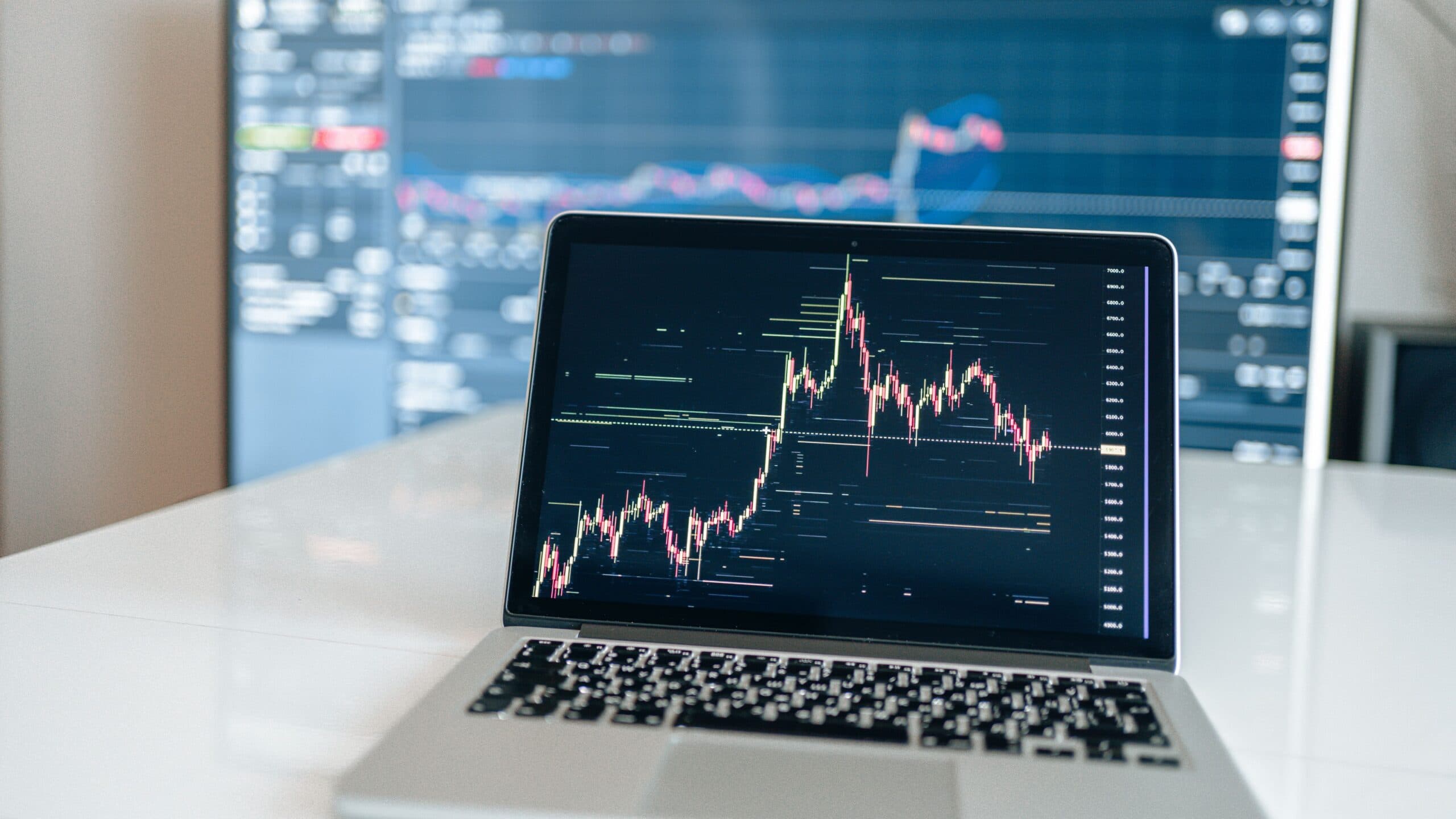 Laptop displaying a stock market candlestick chart on its screen in a trading setup