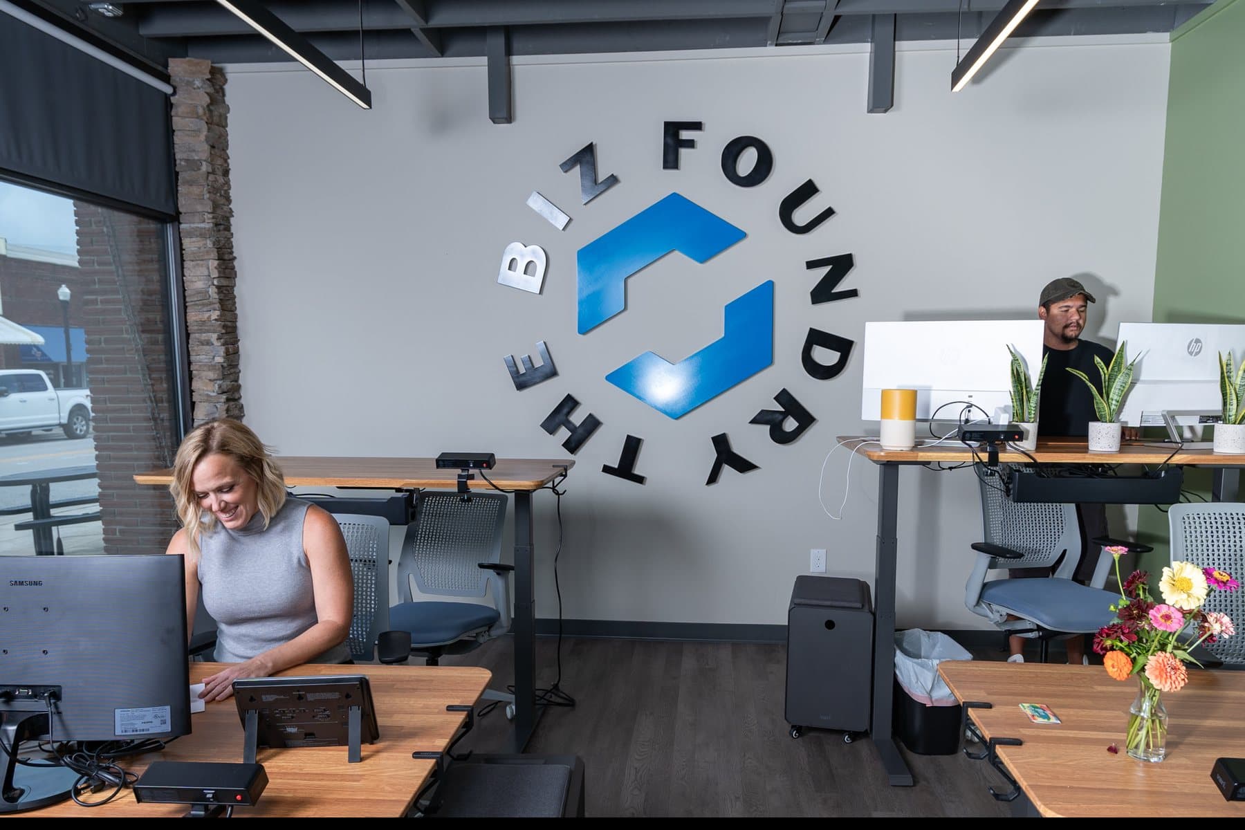 Two members working at dedicated desks under The Biz Foundry mark at WorkBase