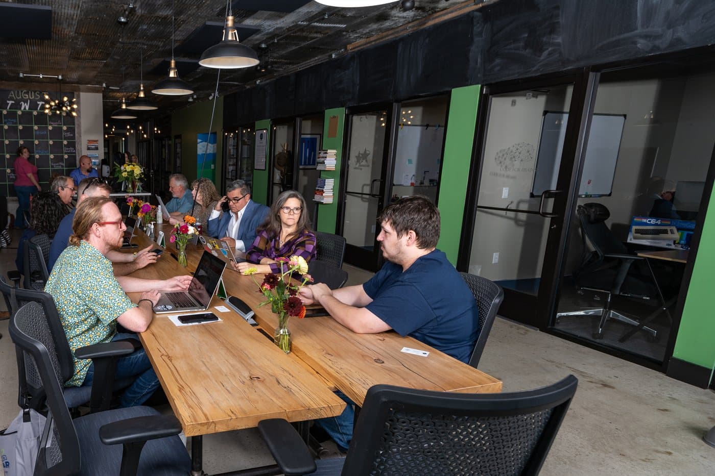 Members working at laptops along the communal tables at WorkBase