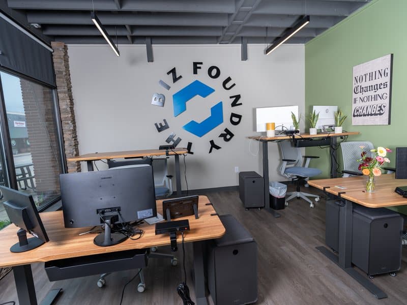 A row of dedicated standing desks with monitors and privacy barriers
