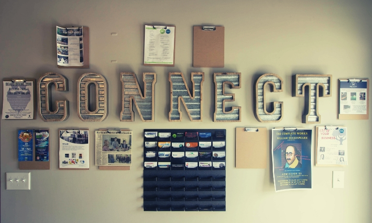 A wall inside The Biz Foundry with the word "Connect" spelled out in aluminum letters. The wall has event flyers and business cards surrounding the letters.