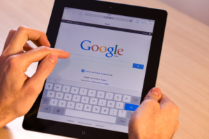 Woman holding iPad typing into Google search bar