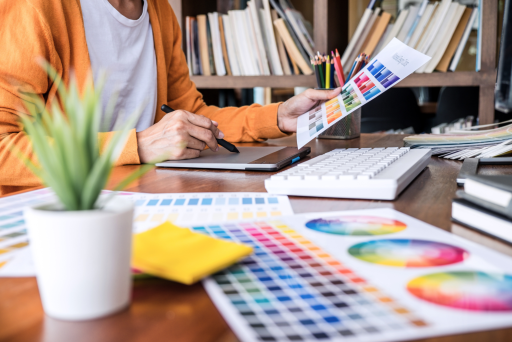 Person sitting at a desk with various Pantone color swatches trying to pick branding colors