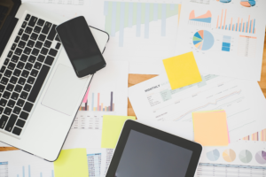 Desk with reports scattered around and laptop