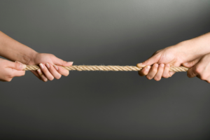 photo of man and woman's hands pulling rope in a tug of war game